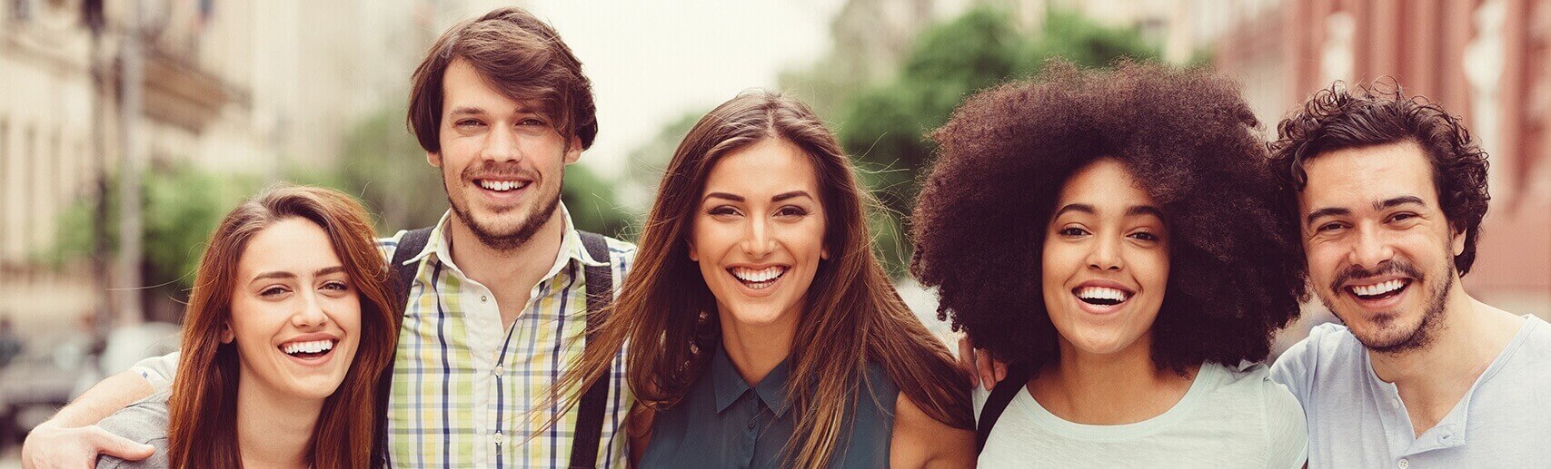 Group of young adults of different races smiling outside