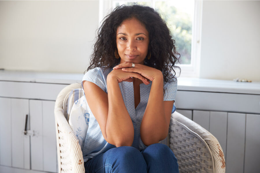 Curly-haired woman leans on her hands while recovering after a tooth extraction in Portland, OR