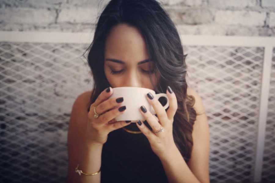 dark haired woman drinking a cup of coffee
