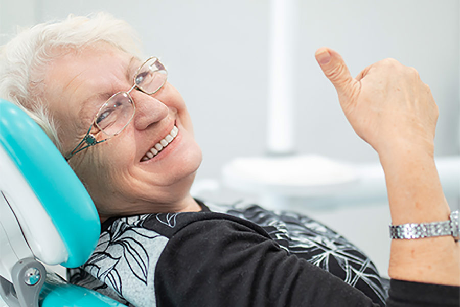 senior woman gives a thumbs up in the dental chair after a successful oral cancer screening