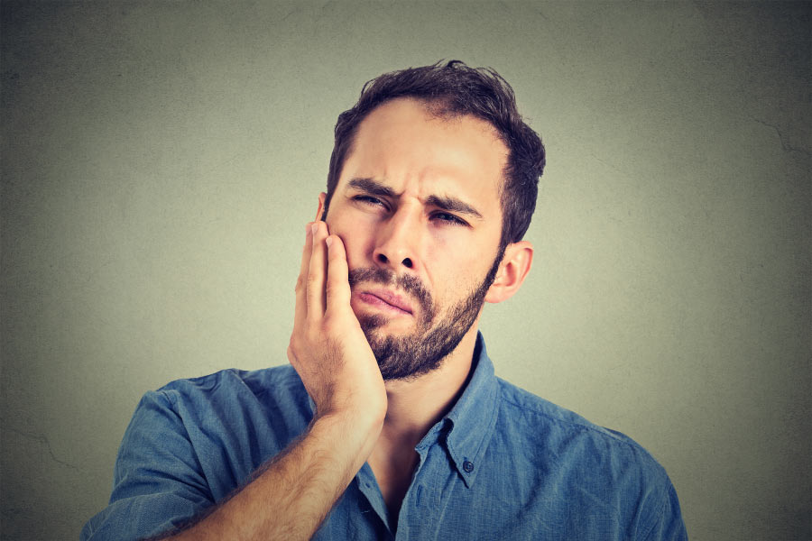 bearded man holds his jaw after losing a tooth