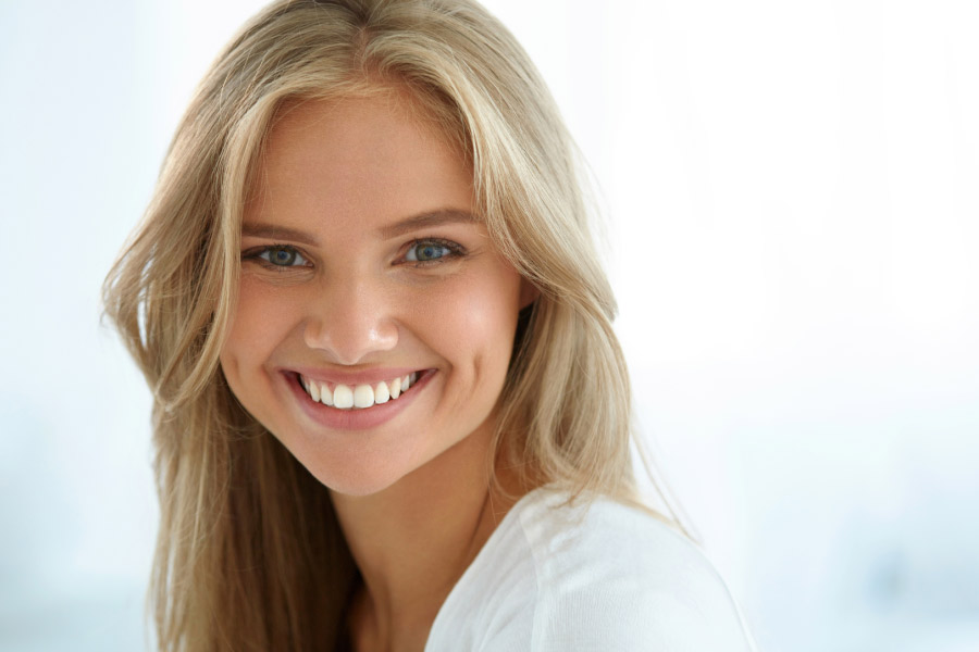 young blond woman smiles to show off her white teeth