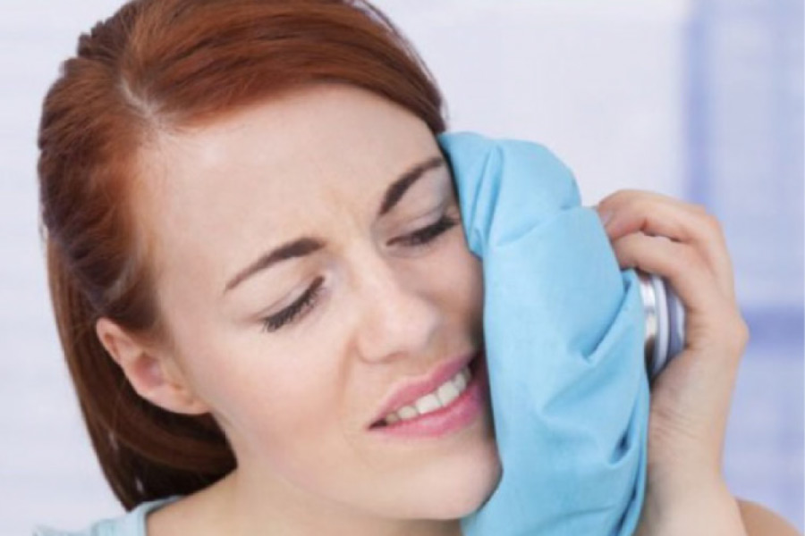woman holds an ice pack to her face after a tooth extraction