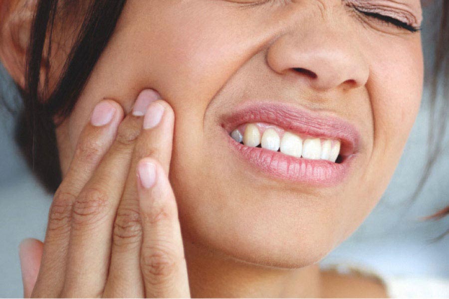 woman holds her cheek in pain from a tooth infection needing a root canal