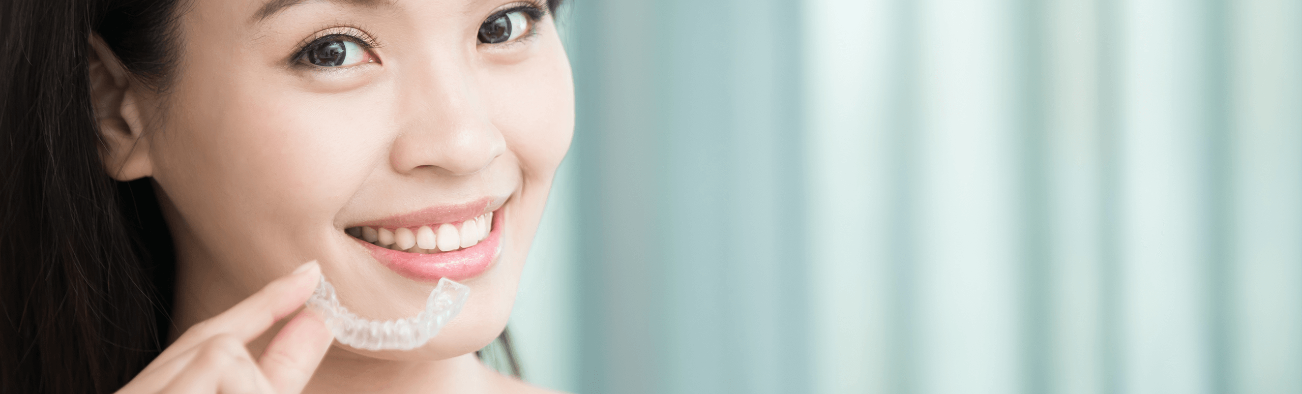 woman holding up her clear aligner