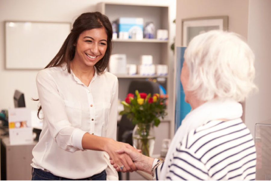 dentist receptionist welcomes a senior patient for an appointment