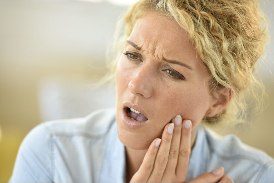 woman holds her jaw with tooth sensitivity