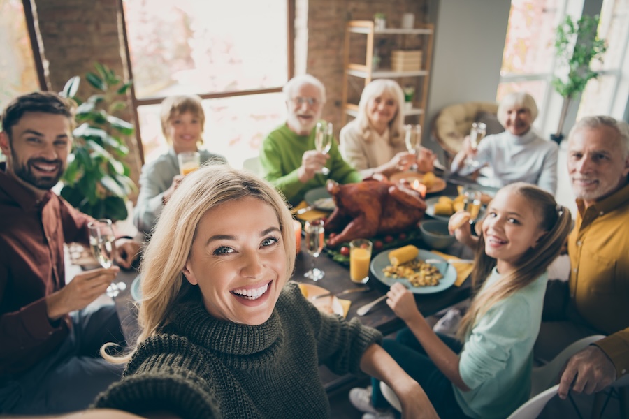 family smiling as a group for a family photo around thanksgiving table, holiday smile prep